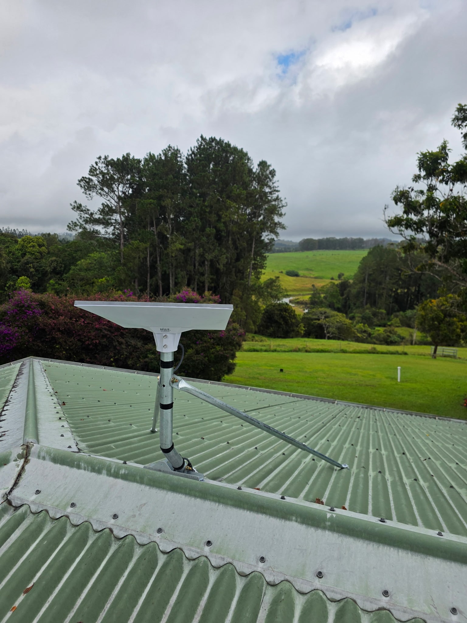 Roof-mounted antenna overlooking green countryside on an On Poynt Communications job